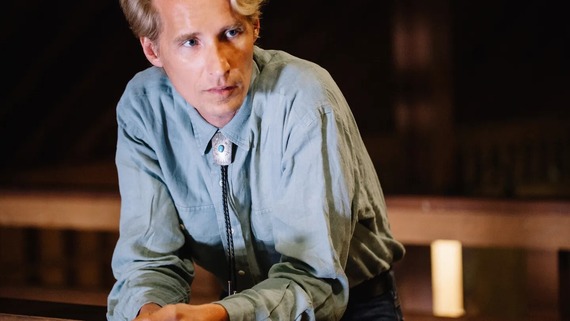 Folk artist Tom Brosseau sitting and putting his elbows on this knees while he looks to the side