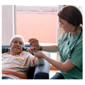Female nurse putting a bracelet on an elderly male patient, sitting in chair.