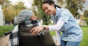 A health care professional conversating with a lady in a wheelchair.