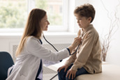 A medical professional examining a young boy.
