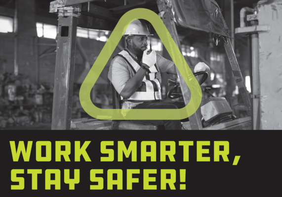 A man sitting in a forklift holding a two-way radio close to his mouth.