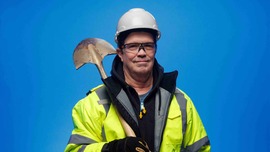 Man holding shovel wearing hard hat and hi vis gear 