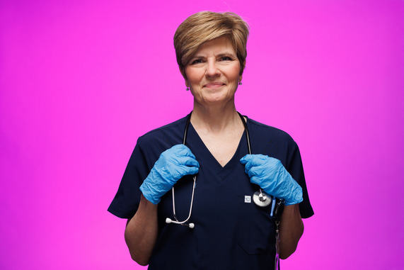 Woman wearing scrubs resting hands on stethoscope