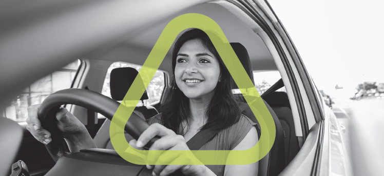 Black and white photo of woman driving a car with the green Get Home Safe triangle surrounding her head