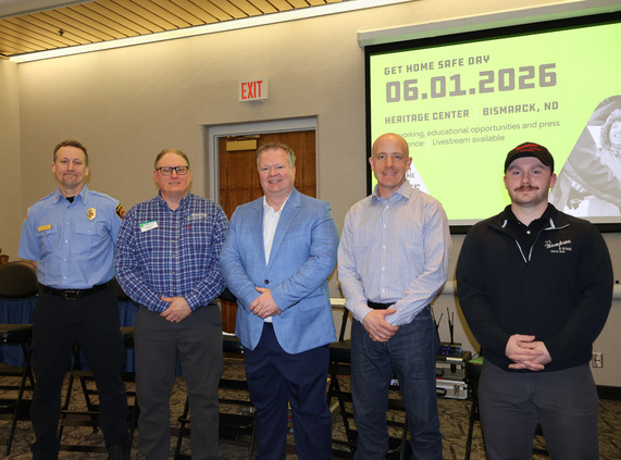 Five panelists stand in a meeting room with the Get Home Safe Day Graphic on a screen behind them