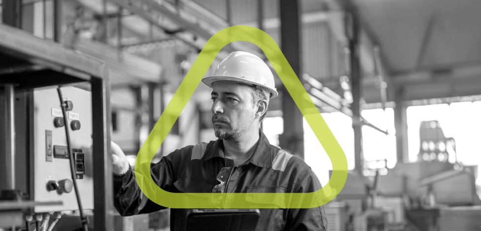 Man in a factory looking at an electrical panel with the green Get Home Safe triangle overlaid around him. 