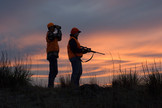 Two firearm deer hunters at sunset