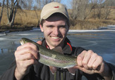 Young man holding up a trout he caught ice-fishing