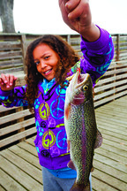 A girl holding up a trout she caught