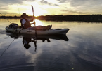 Silhouette of someone kayaking at sunset