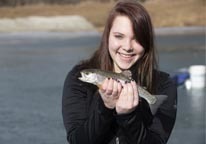 Girl holding a rainbow trout she caught ice fishing