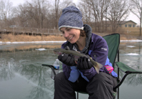 Woman holding fish while ice fishing