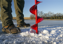 An angler using a hand auger to drill a hole in the ice