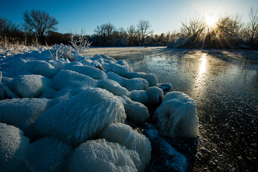 Round snow formations with sun shining on lake