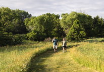 A couple walks a grassy trail at Victoria Springs State Recreation Area.