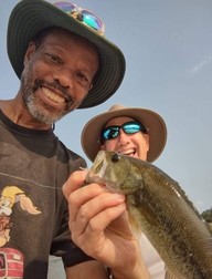 Two people smiling and holding up a fish