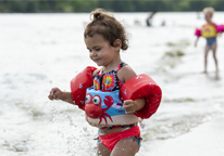 Little girl playing in the water wearing a life jacket.