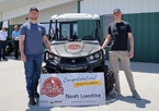 Luedtke and Cuddy standing with the grand prize John Deere Gator