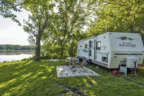 A camper sits beside his RV at a lakeside campground at Alexandria State Recreation Area.