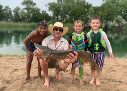 Man and three boys holding a fish