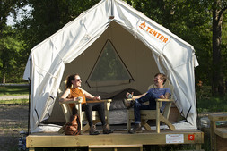 A couple sitting in Adirondack chairs in front of Tentrr campsite