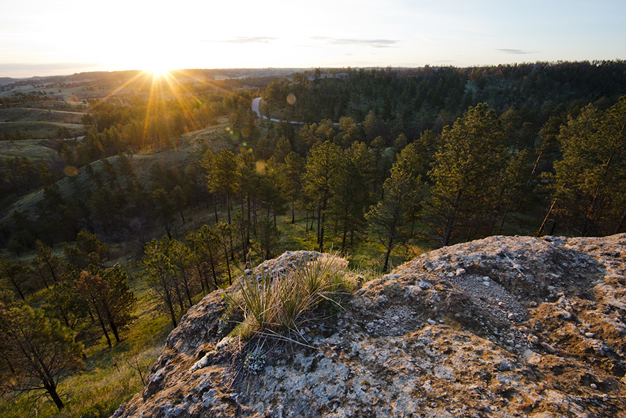 Sun peeking over horizon, illuminating bluffs and overlook at Chadron State Park.