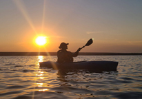 Silhouette of person kayaking at sunset