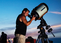 Man gazing through a telescope at night sky