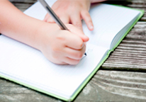 Someone writing in a notebook on a park bench