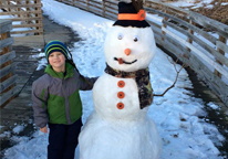 Boy standing next to snowman