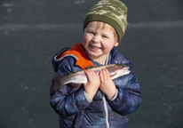 Boy holding up a fish he caught ice-fishing