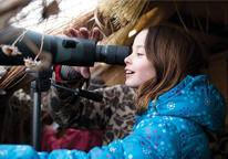 Girl looking through telescope in bird blind at Marsh Madness