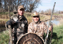 Father and son posing by harvested turkey