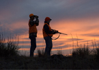 Two firearm deer hunters at sunset