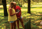 Girls standing by a Great Park Pursuit post with a cell phone