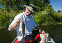 Man holding up a fish in a boat