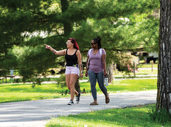 Two friends walking through a park and looking around