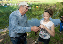 Youth fishing instructor working with a girl