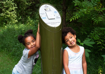 Two girls standing by Great Park Pursuit post