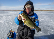 Man holding a largemouth bass he caught ice-fishing