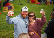 Couple smiling and holding up wine glasses at Sip Nebraska festival