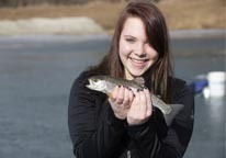 Woman holding up a rainbow trout she caught while ice-fishing