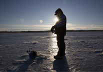 Silhouette of an angler ice-fishing