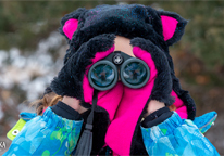 Girl bundled up for winter, looking for birds with binoculars