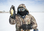 Angler holding up a fish he caught while ice-fishing