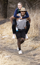 Couple hiking a state park trail, with guy carrying girl on his back