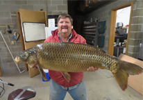 Angler holding a 39-pound common carp caught by rod and reel