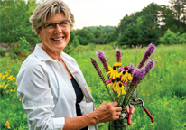 Sue Kirkpatrick posing with freshly cut wildflowers from her prairie restoration