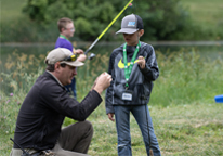 Youth fishing instructor helping a boy fish