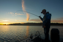 Silhouette of angler fishing at sunset